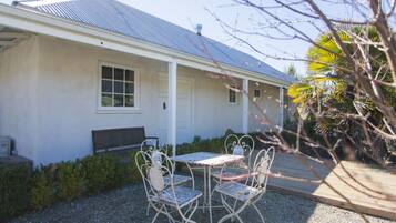 A building with a metal roof, a porch, and a gravel patio with metal chairs and a table.