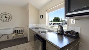 A modern kitchen with a built-in oven, a sink, and a window with a view of the street. - 171 On High Motel (Blenheim)