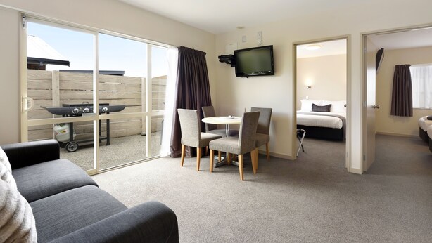 A hotel room with a balcony, a dining area, a TV, and a bed. - 171 On High Motel (Blenheim)