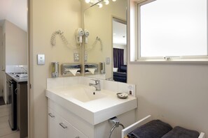 A modern bathroom with a large mirror, a white sink, a hairdryer, and a towel rack. - 171 On High Motel (Blenheim)