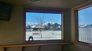 A room with a window overlooking a snowy landscape with mountains.