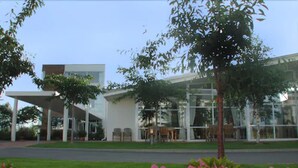 A modern building with a glass facade, outdoor seating, and a well-maintained lawn.