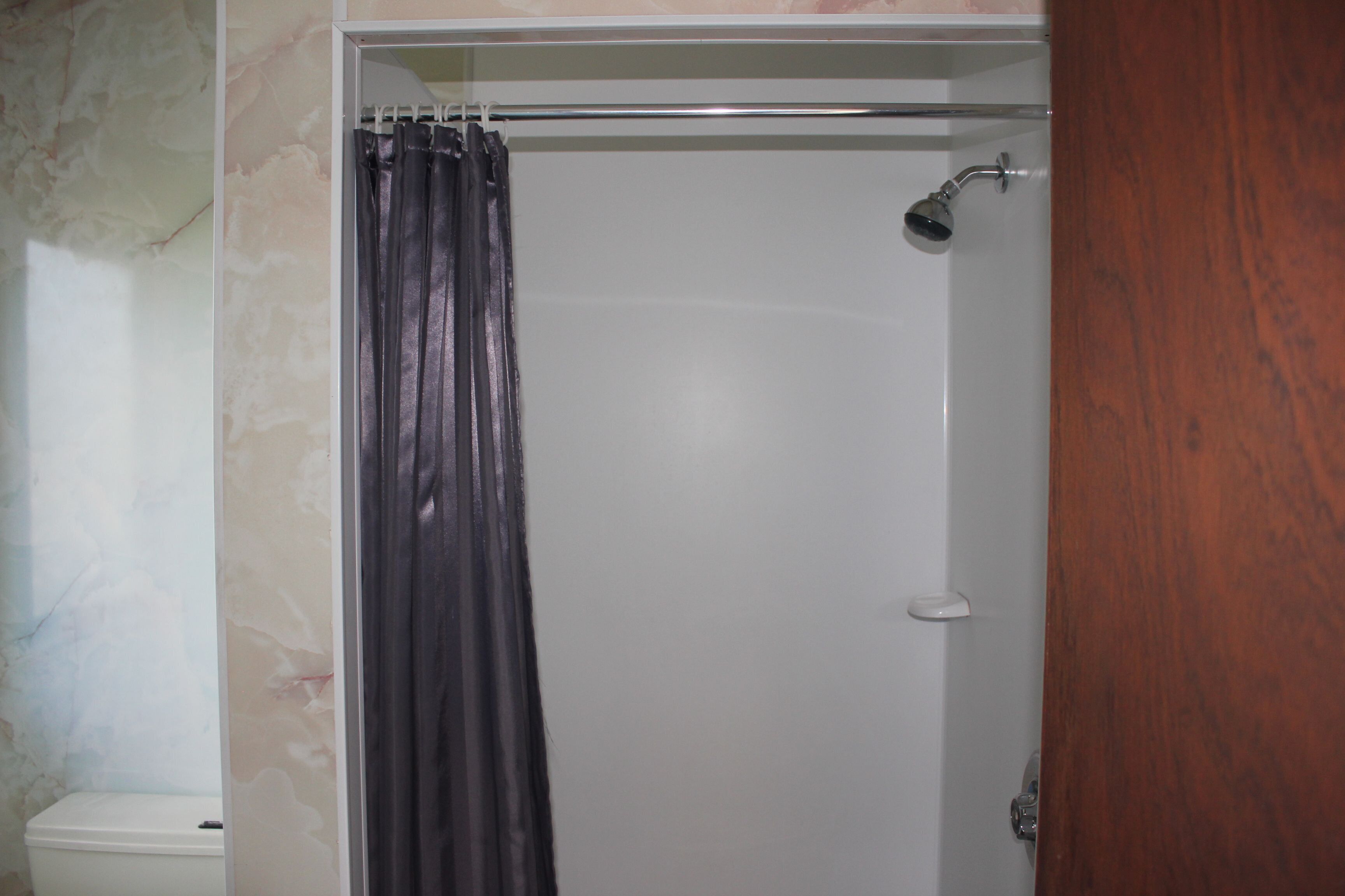A shower enclosure with a showerhead and curtain.
