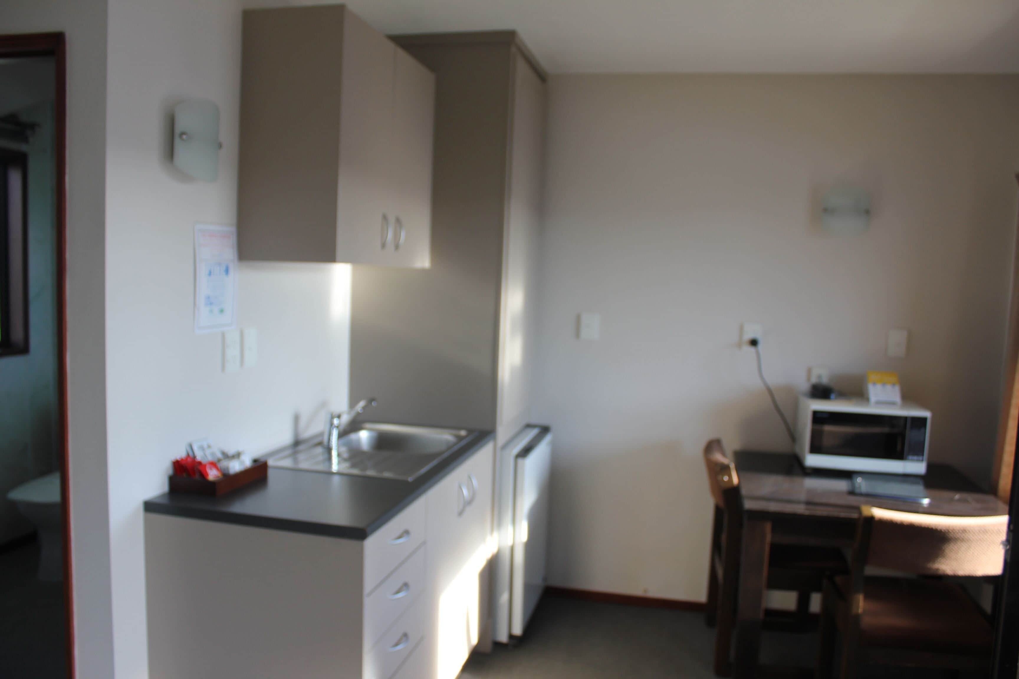 Una cocina compacta con pileta, microondas y comedor con mesa y sillas.