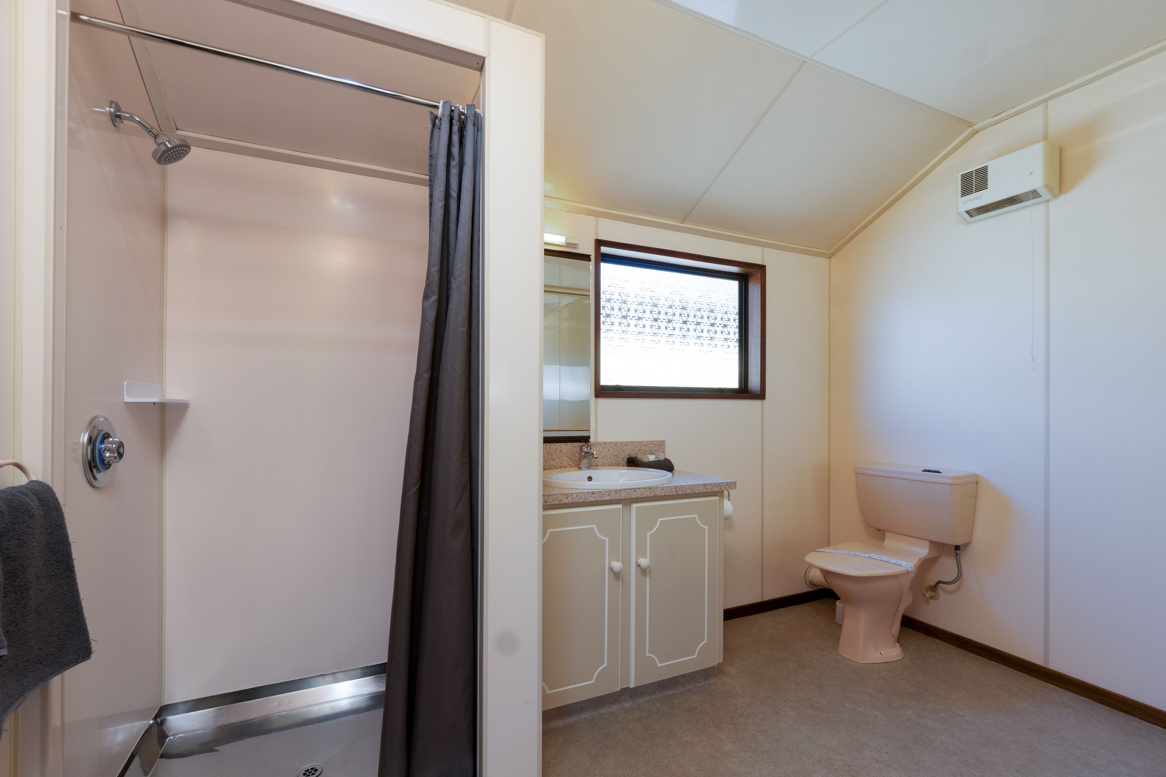 A bathroom with a shower, toilet, sink, and cabinet.