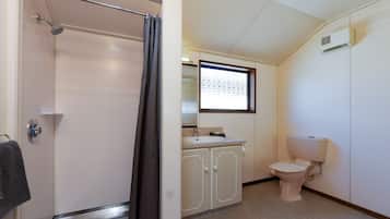 A bathroom with a shower, toilet, sink, and cabinet.