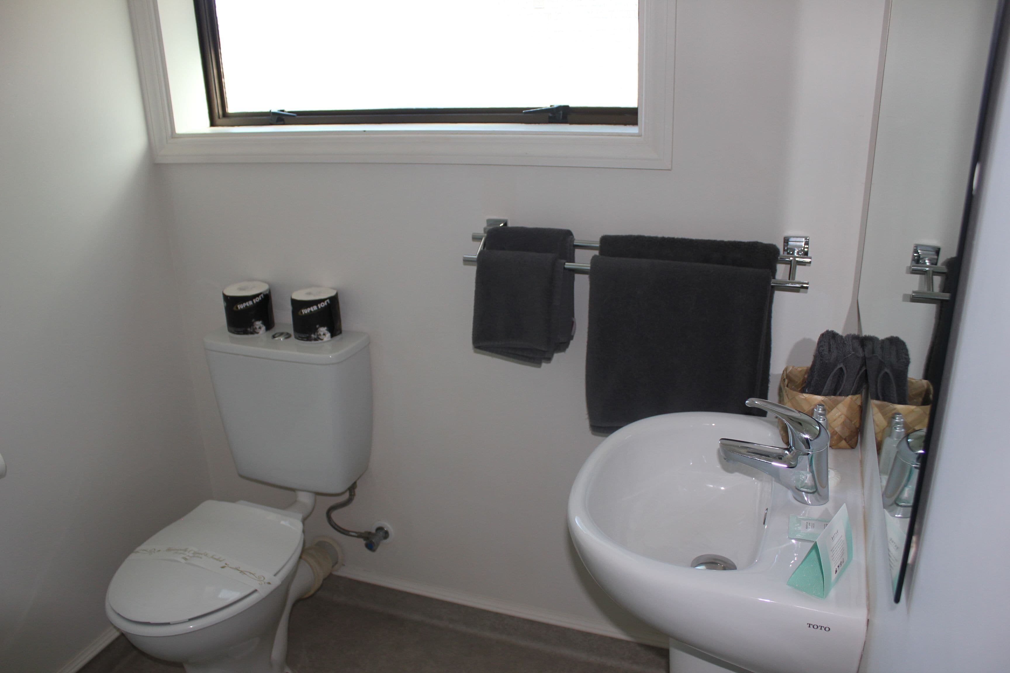 Un baño con inodoro, lavabo y una ventana sobre el lavabo.