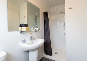 A modern bathroom with a white sink, mirror, and shower.