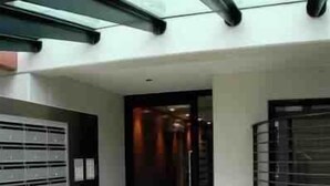 A modern building with a tiled floor, a glass door entrance, and a metal railing. - City West Accommodation (Perth)