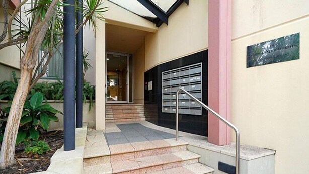 A building entrance with a set of stone steps, a metal handrail, and a mailbox on the wall. - City West Accommodation (Perth)