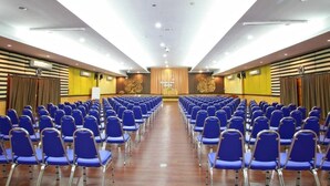 A conference room with rows of blue chairs facing a stage with a podium. - Pung Waan Kwae Noi Resort (Sai Yok)