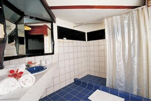 Un baño con piso de azulejos azules, un lavamanos blanco y una cortina de ducha.