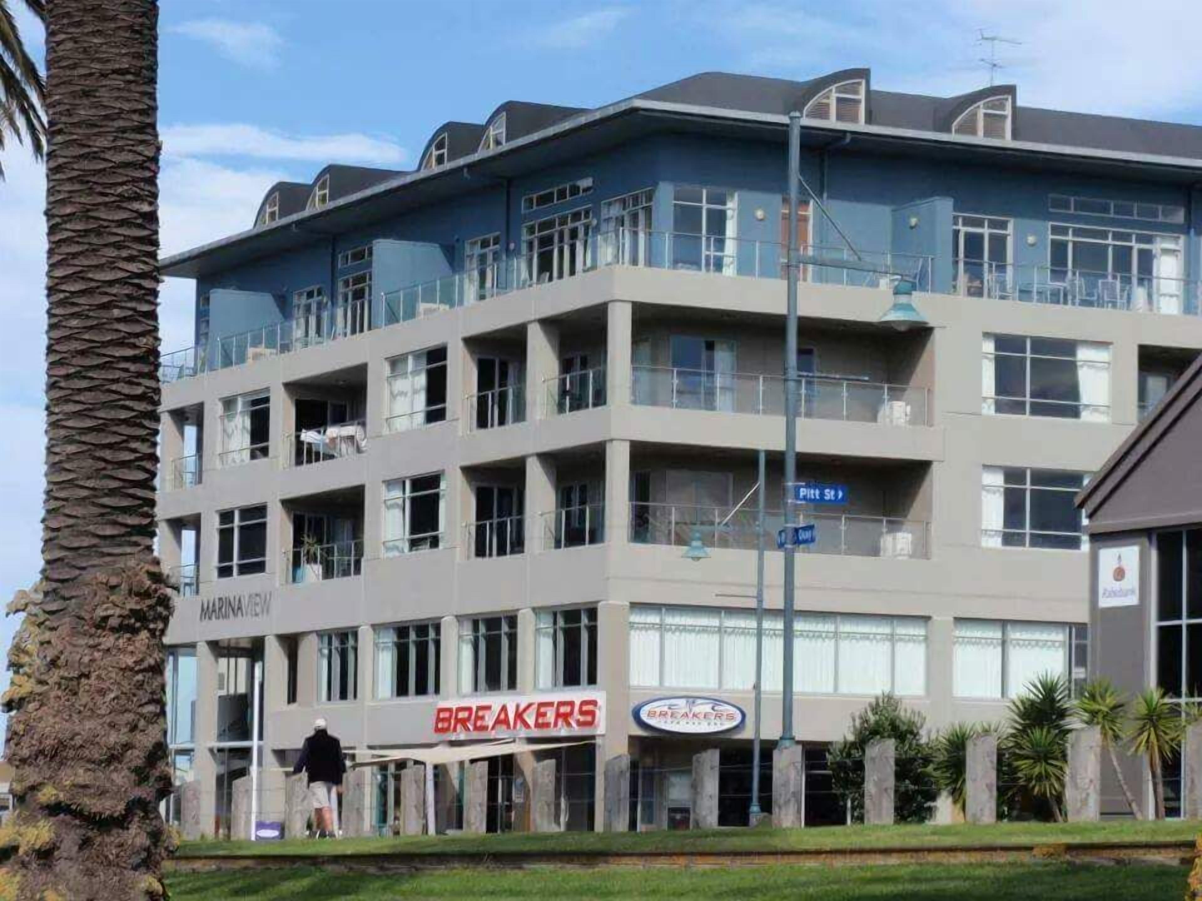 Un edificio de varios pisos con un restaurante 'BREAKERS' en la planta baja.