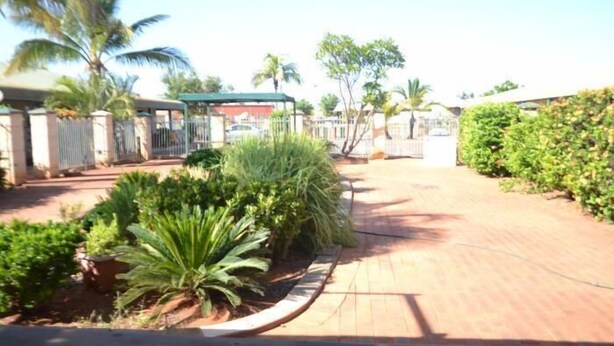 A paved pathway leading to a gated entrance with a covered structure. - South Hedland Motel (South Hedland)