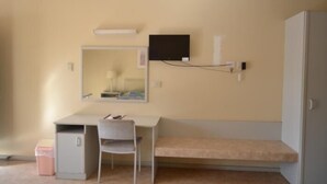 A small, compact room with a desk, chair, and a bed. - South Hedland Motel (South Hedland)