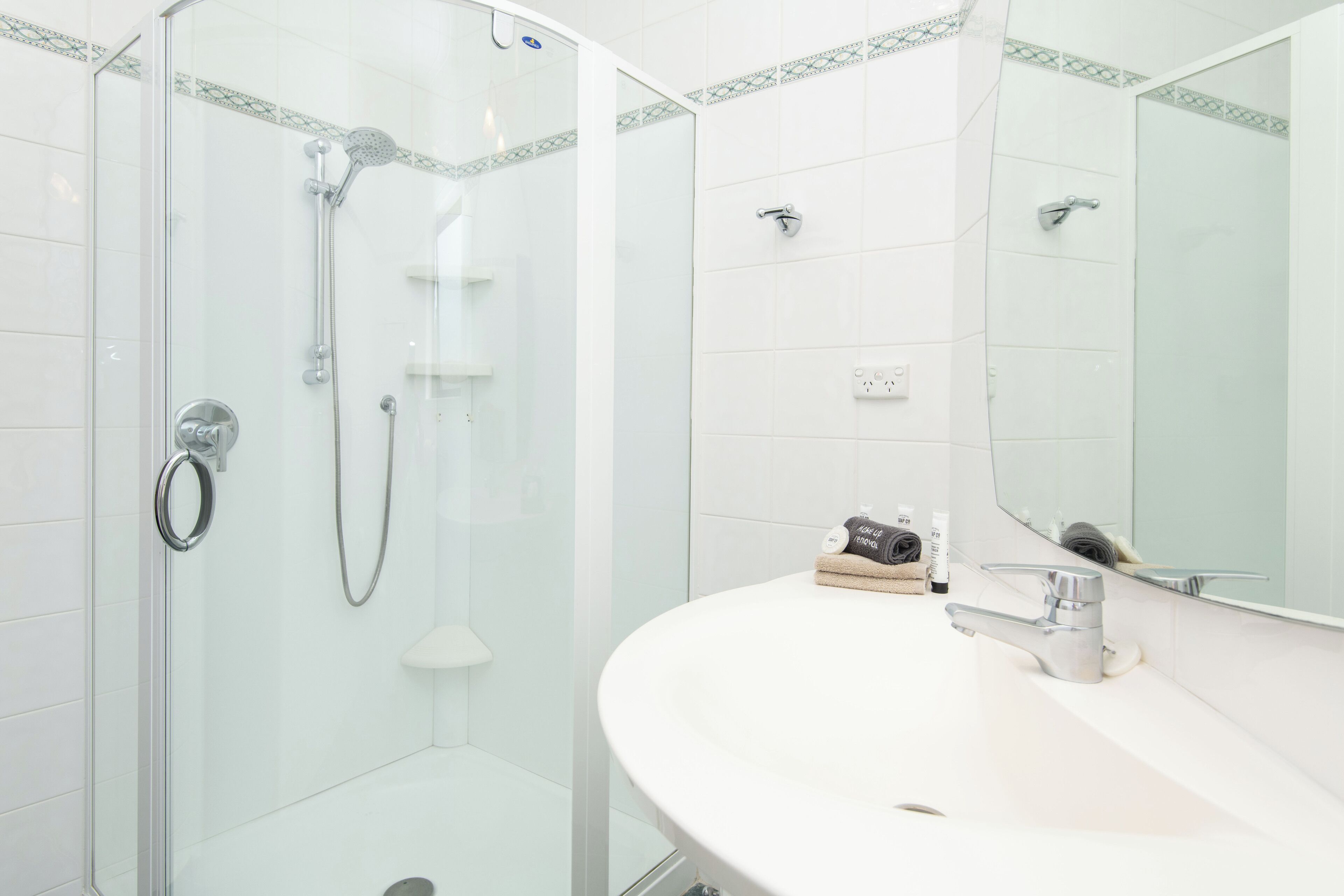 A modern bathroom with a glass-enclosed shower, a white sink, and a large mirror.