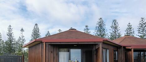 A wooden cabin with a balcony, surrounded by trees.