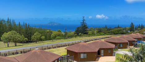 A row of cabins with a view of the ocean and a distant island.