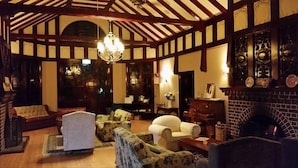 A traditional room with a high ceiling, exposed wooden beams, a fireplace, and classic furniture. - Petersons Armidale Winery & Guesthouse (Armidale)