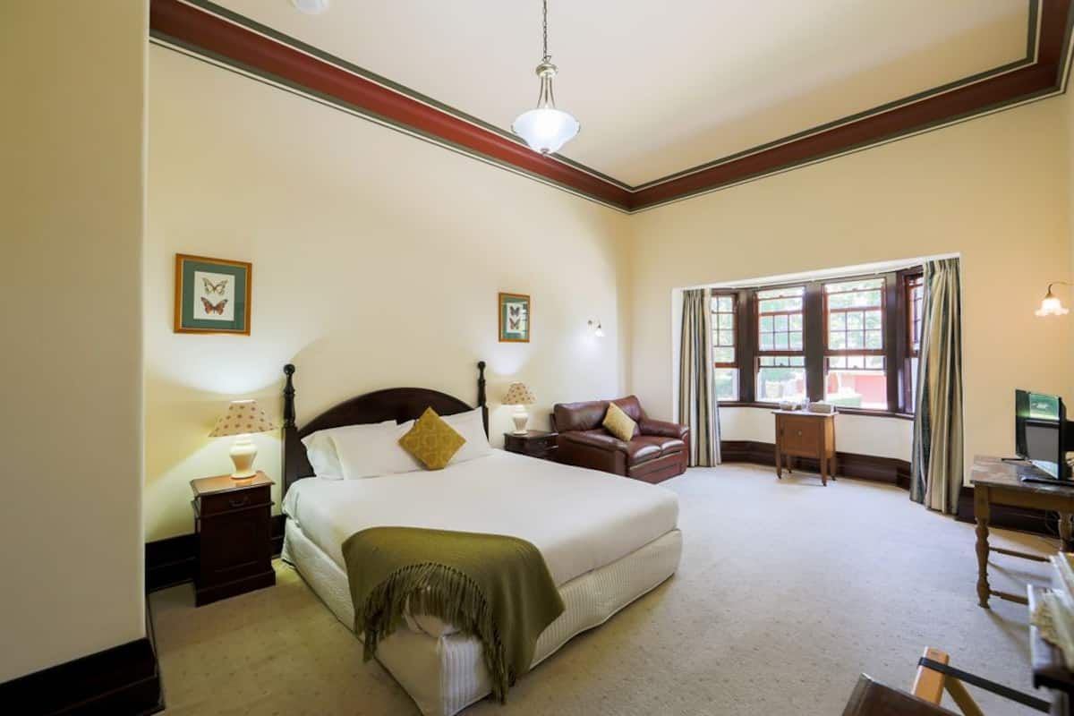 A hotel room with a large bed, a desk, and a window with curtains.