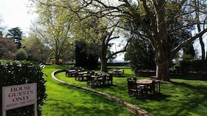 A garden area with outdoor seating, a sign indicating it's for house guests only, and a view of the sea in the background. - Petersons Armidale Winery & Guesthouse (Armidale)