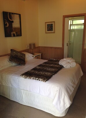 A neatly made bed with a leopard print throw, a bedside lamp, and a framed picture on the wall. - Yarraglen BnB (Yarra Glen)