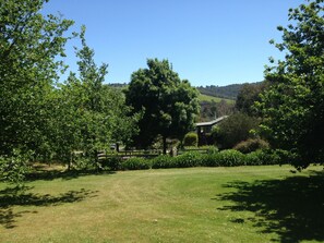 A grassy field with a wooden fence, trees, and a building in the background. - Yarraglen BnB (Yarra Glen)