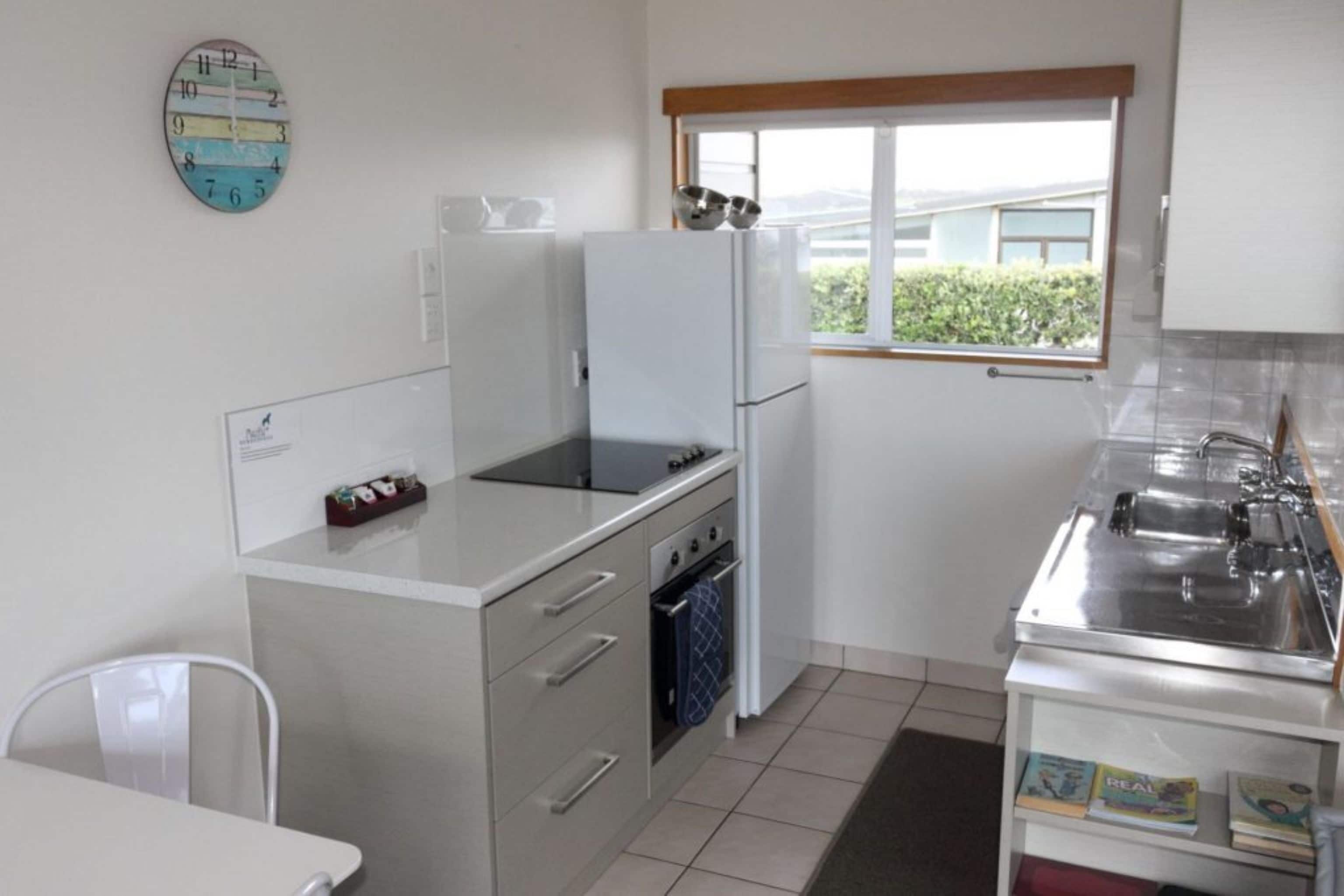 Eine kompakte Küche mit Kühlschrank, Herd, Backofen und einem Fenster mit Blick.