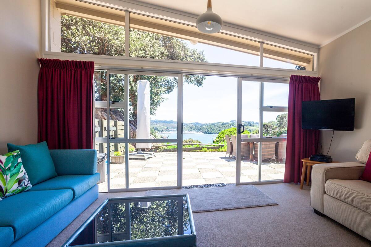A living room with a sofa, a coffee table, a TV, and a large sliding glass door leading to an outdoor patio.