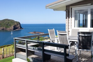 A deck with outdoor seating overlooking a body of water and a distant island.