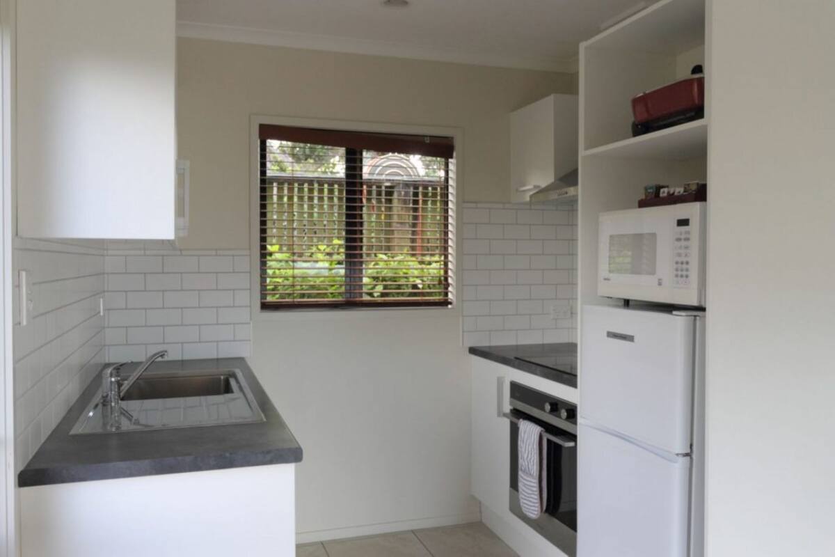 A compact kitchen with a sink, stove, oven, and microwave.