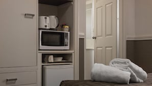 A hotel room with a bed, a microwave, a refrigerator, and a door leading to another room. - City Motor Inn Toowoomba (South Toowoomba)