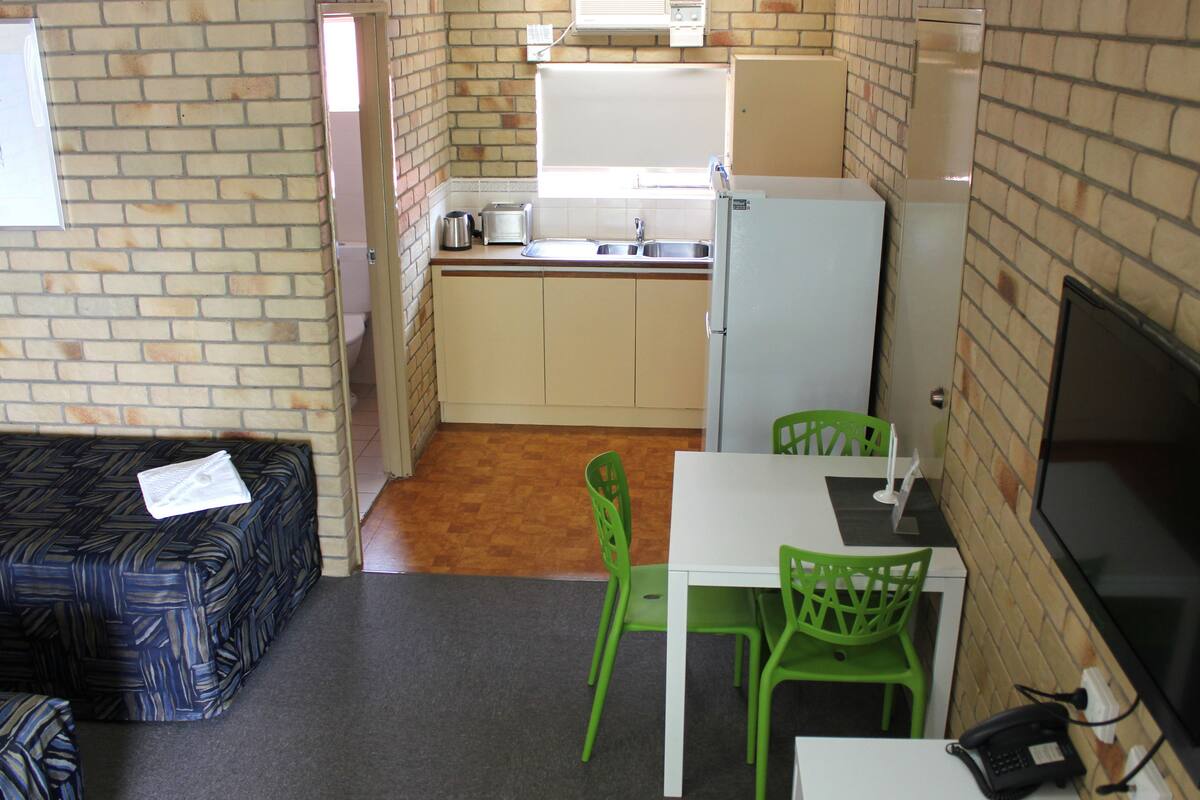 A compact kitchen with a refrigerator, sink, and a small dining area with two chairs.