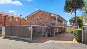 A two-story building with a brick facade, a covered parking area, and a gated entrance. - City Motor Inn Toowoomba (South Toowoomba)