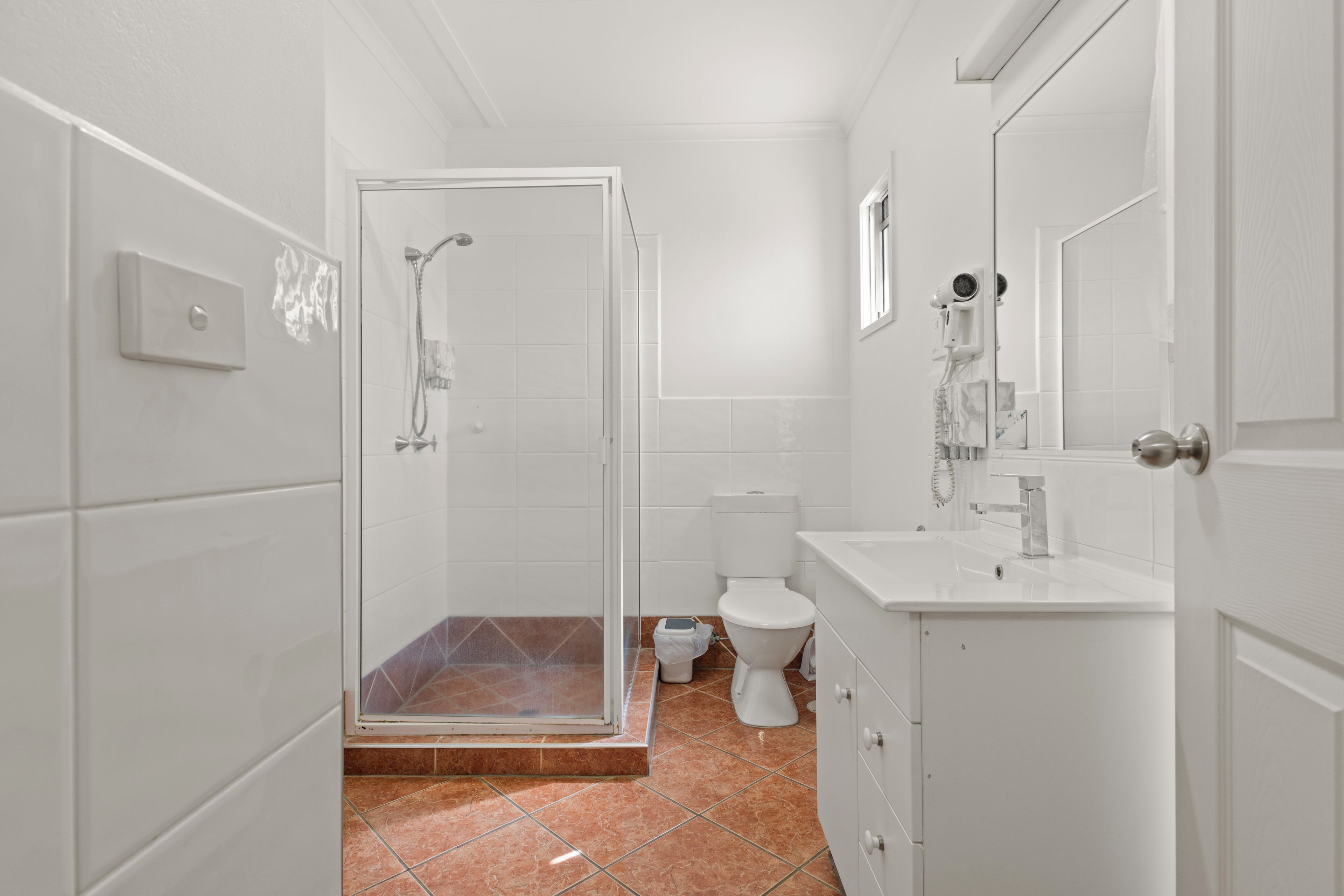 A modern bathroom with a glass shower enclosure, a white toilet, and a sink with a mirror.