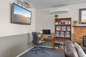 A modern office space with a desk, computer, bookshelf, and a large framed picture. - City Motor Inn Toowoomba (South Toowoomba)