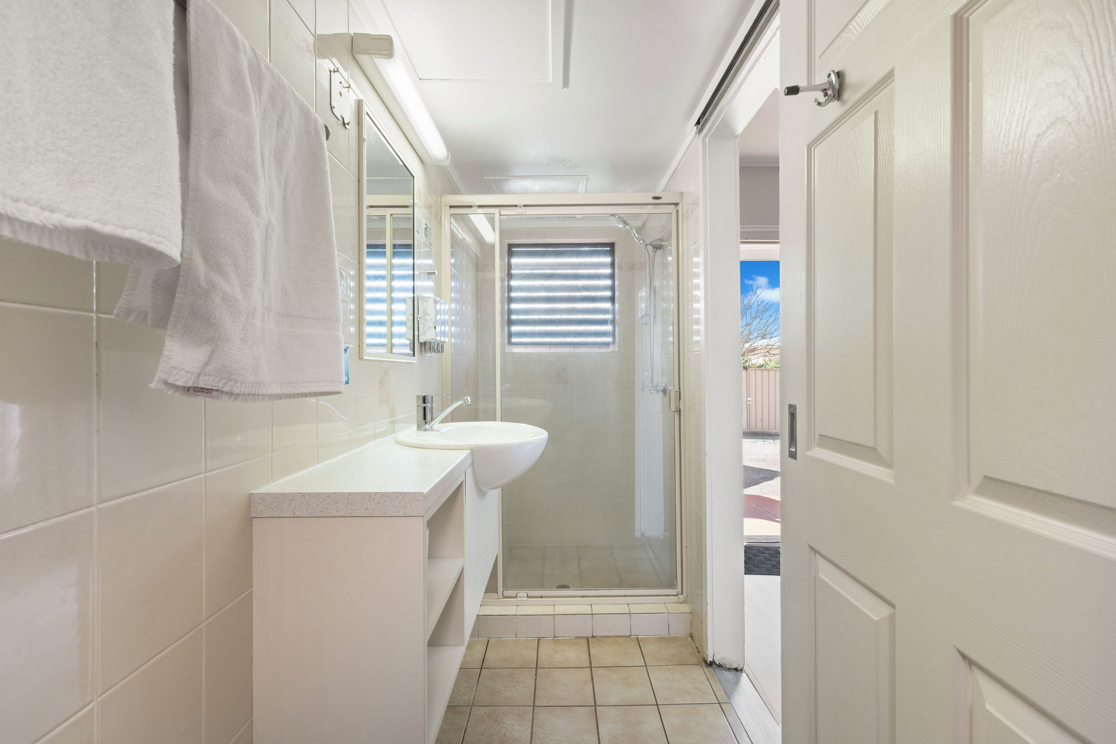 A bathroom with a shower, a sink, and a mirror.