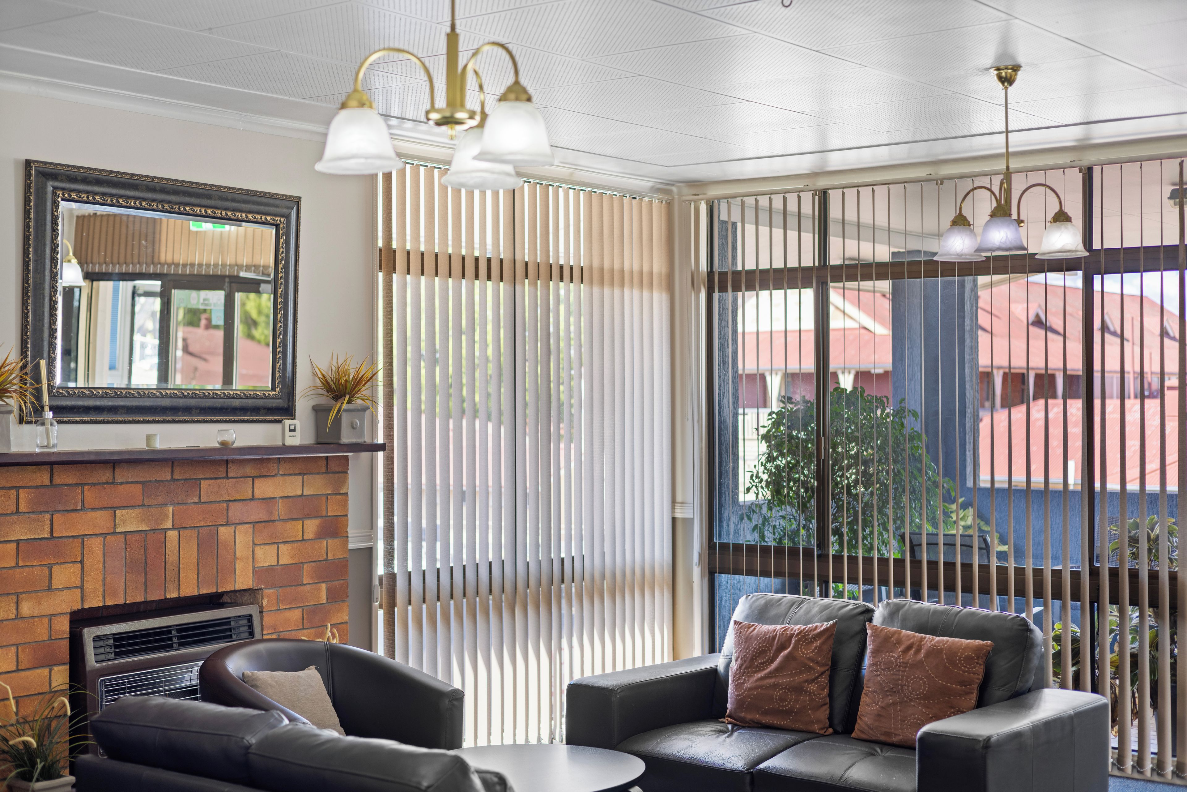 A modern living room with a fireplace, leather sofa, and a large window with blinds.