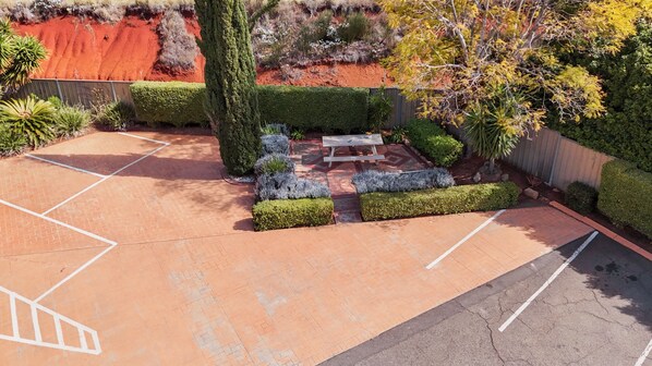 Un espace de stationnement agrémenté d’une table de pique-nique et de haies soigneusement taillées.