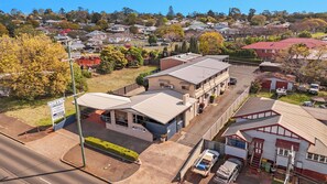 A motel with a flat roof, a parking area, and a sign indicating availability. - City Motor Inn Toowoomba (South Toowoomba)
