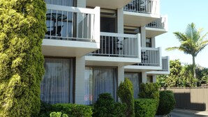 A multi-story building with balconies, large windows, and surrounding greenery. - East Port Motor Inn (Port Macquarie)