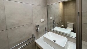 A modern bathroom with a large mirror, a white sink, and a toilet. - Ryley Motor Inn (Wangaratta)