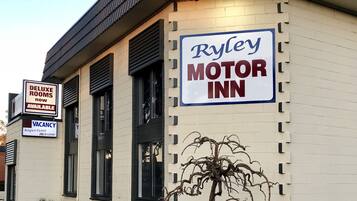 Un edificio con un'insegna che riporta "Ryley Motor Inn" e un'altra che indica "Camere Deluxe Disponibili Ora".