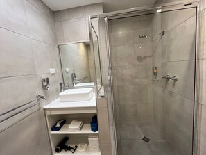 A modern bathroom with a glass-enclosed shower, a white sink, and a mirror.