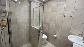 A modern bathroom with a glass shower enclosure, a toilet, and a sink.
