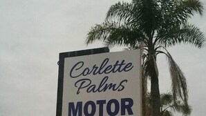 Une enseigne indiquant « Corlette Palms Motor Inn » avec un numéro de téléphone.