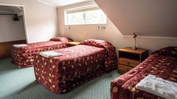 Un dormitorio con dos camas, una ventana, una mesita de noche y un armario.