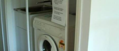 A compact laundry area with a washing machine and a drying rack.