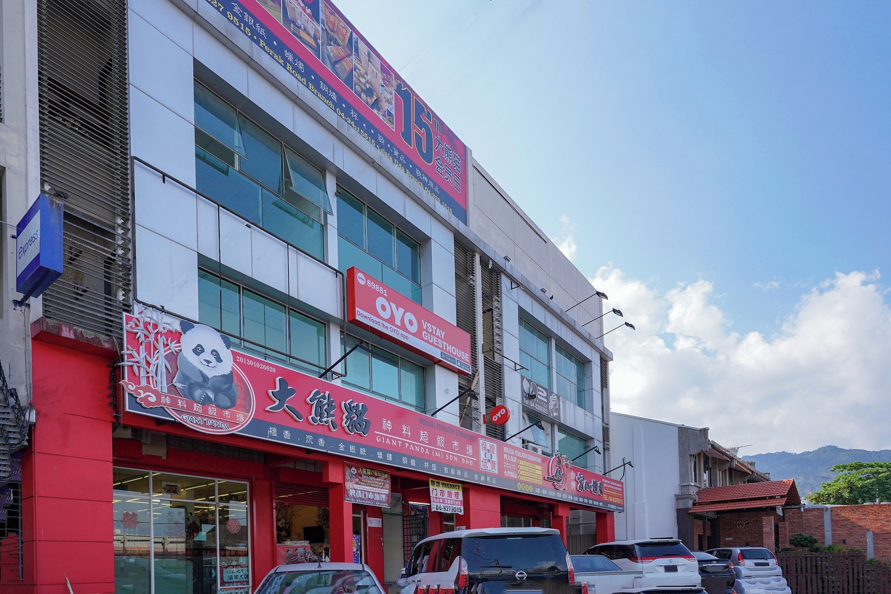 A multi-story building with various commercial establishments on the ground floor, including a panda-themed shop and a guesthouse.