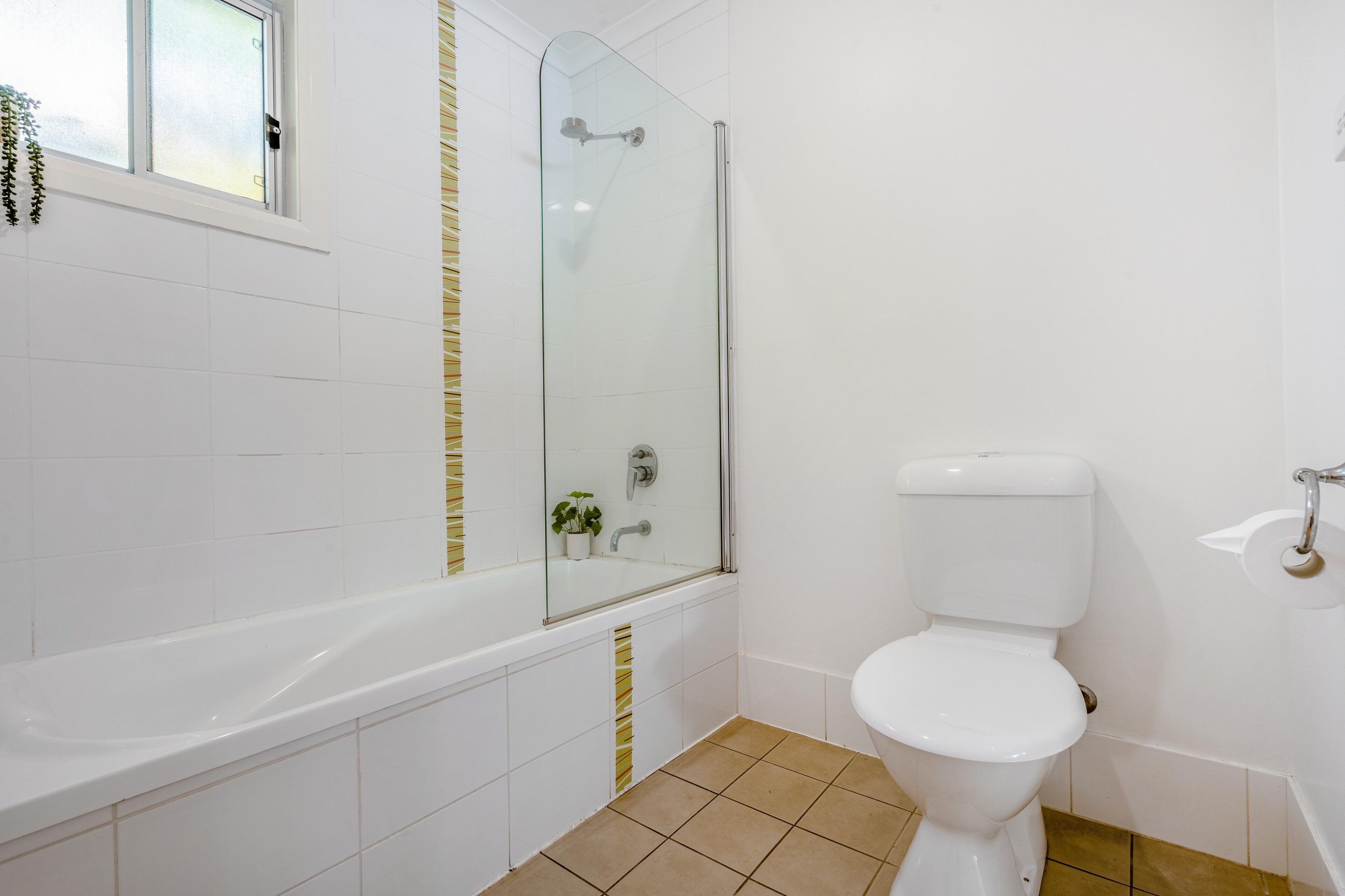 A bathroom with a white bathtub, a glass-enclosed shower, and a white toilet.